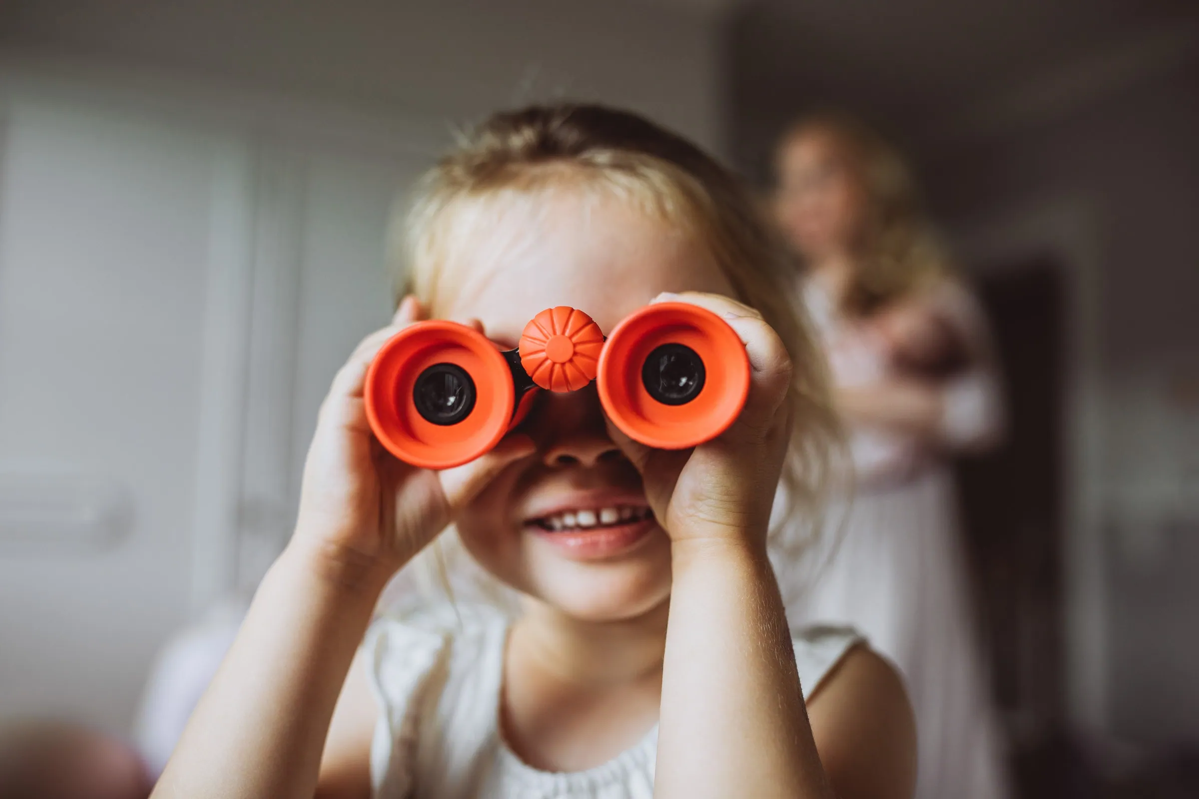 Kind schaut spielerisch durch ein rotes Fernglas